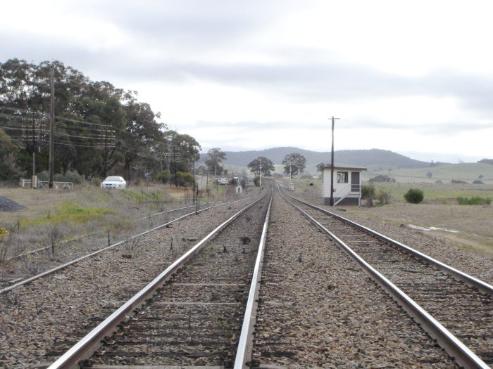 The view looking south past the one-time station location. The platform was situated where the signal box now stands, with the up main curving around behind it.