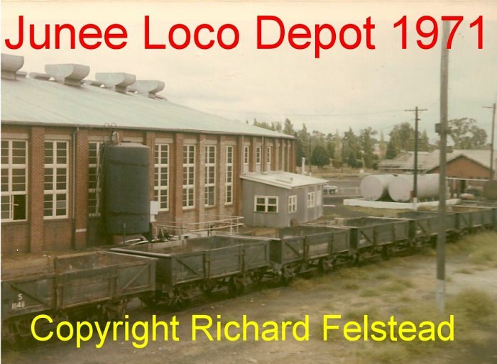 A row of 4-wheel wagons sits outside the roundhouse building.