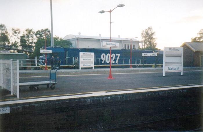 
An up loaded coal train hauled by three 90 class locomotives has stopped
for a crew change.  Several different styles of signage are visible.
