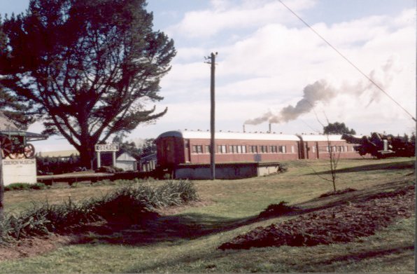 A pair of preserved passenger carriages sit adjacent to the station.