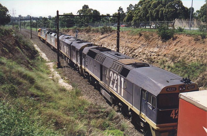 
National Rail train hauled by NR62/G519/8045/42211 has just halted
on the line, after arriving from Melbourne.  It is about to back up
along the Chullora - Sefton goods line and into NR's goods yard.
