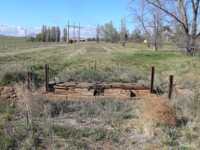 Having crossed the road, the formation crosses the remains of a culvert/cattle grid. Beyond this was a short run-around siding before the track curved off the to right in the distance.