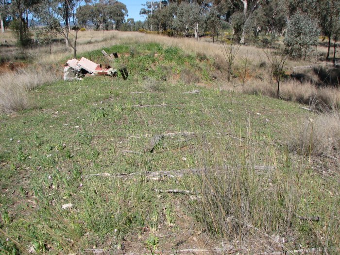 The view looking north east approximately 100 metres east of the branch. Decaying sleepers remain embedded in earth, leading to the remains of a small bridge.