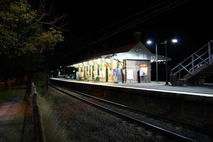 A photo taken after dark from under the footbridge over the highway on the Up side of Valley Heights station. Photo is taken looking towards Sydney showing the Up main and Platform 1.