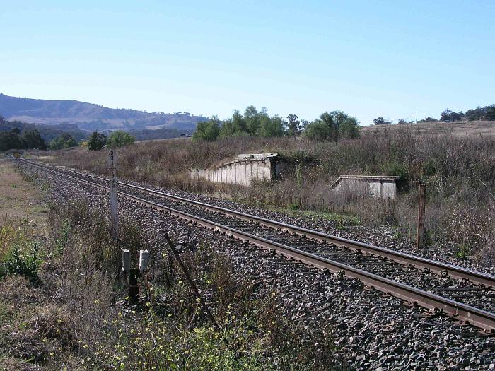 
A view looking north, showing the remains of the goods and stock loading
platforms.  The one-time goods shed and crane were located beyond the banks.
